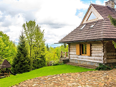 A log cabin with a stone patio and trees.